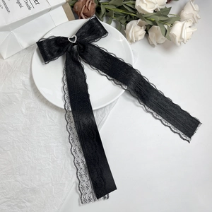 Detail of black lace bow hair clip with heart rhinestone and long elegant streamers