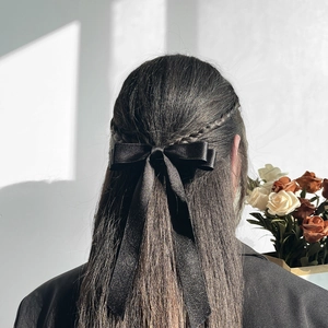 Close-up of elegant black satin ribbon hair bow worn on a braided hairstyle