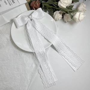 Detailed macro view of white lace hair clip with heart rhinestone and long ribbons
