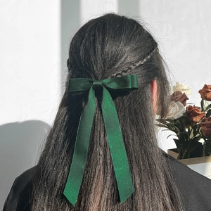 Detailed back view of a dark green bow hair clip with long ribbons and satin shimmer