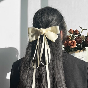 Elegant cream silk bow hair clip with rose center and long streamers on model