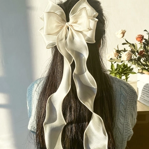 Große cremefarbene Satin-Schleife Haarspange mit langen Bändern auf dunklem Haar