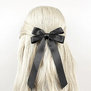Elegant black satin bow hair clip with long ribbons on wavy blonde hair for women