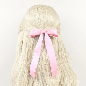 Fiocco per capelli in raso rosa con lunghi nastri su capelli biondo chiaro