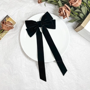 Elegant black velvet oversized bow hair clip with long ribbons on white plate