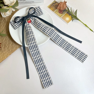 Vue détaillée du nœud papillon à carreaux bleu marine avec un pendentif fraise rouge