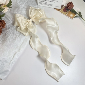 Detailansicht der cremeweißen Satin-Schleifen-Haarspange mit langen fließenden Bändern