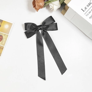 Close-up of black satin ribbon hair clip with elegant silk texture on white background