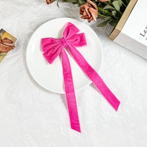 Elegant magenta velvet bow hair clip with long ribbons on a white decorative display