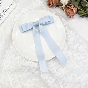 Detail of light blue satin ribbon hair clip with long streamers on a lace background