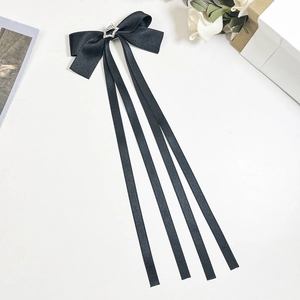 Détail d'une longue pince à cheveux en satin noir avec étoile scintillante et longs rubans