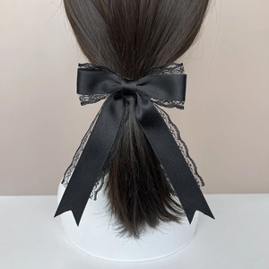 Gothic lace bow hair clip with long satin ribbons shown on ponytail on a model