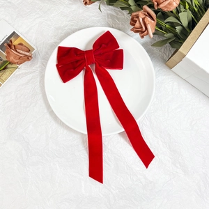 Macro view of high-quality red velvet bow hair clip with elegant long vertical ribbons