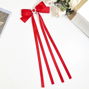 Détail d'un nœud papillon rouge en soie avec étoile en strass et longs rubans