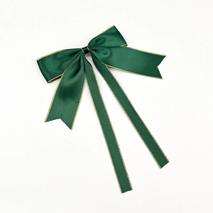 Détail d'une pince à cheveux avec nœud en satin vert foncé et bordure dorée élégante