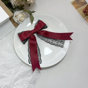 Detailed view of dark red satin bow with black lace trim on a white decorative plate