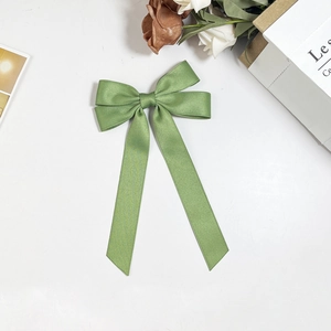 Close-up of light green satin bow hair clip with elegant long ribbons on a white background