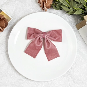 Pink velvet bow hair clip with elegant long ribbons on a decorative white porcelain plate