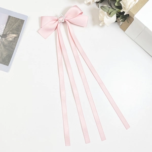 Détail d'une pince à cheveux nœud en satin rose avec strass étoile et longs rubans en soie