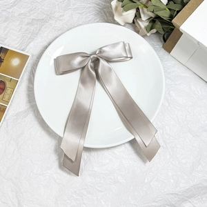 Dettaglio elegante fermaglio per capelli in raso oro champagne con lunghi nastri decorati