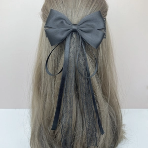 Elegant black satin hair clip with long lace ribbons shown on light brown hair