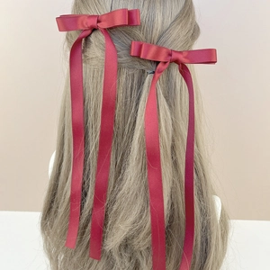 Detail view of burgundy satin ribbon bow hair clips with long streamers on long brown hair