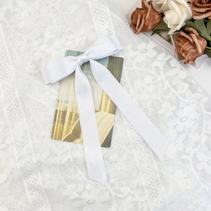 Detail of white satin bow hair clip with long ribbons on elegant lace and dried flowers