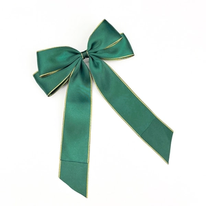 Detail shot of a dark green satin bow hair clip with elegant gold stitched edges