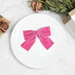 Detail of a sweet pink velvet bow hair clip with soft texture on a white background