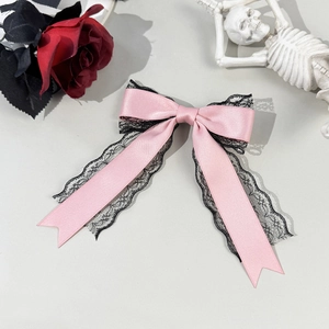 Detailed view of pink satin bow hair clip with black lace trim and gothic doll style