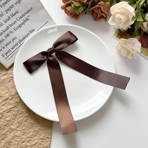 Détail de la barrette à nœud en satin marron café avec rubans sur plateau céramique