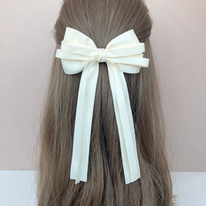 Close-up of elegant cream satin layered bow hair clip with long ribbons on model hair