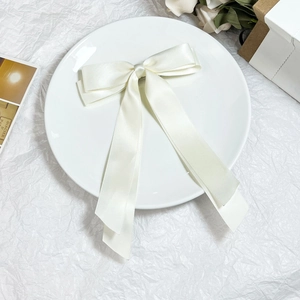 Dettaglio del fermaglio per capelli in raso bianco crema con lunghi nastri eleganti