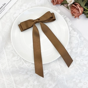 Detailed close-up of a brown satin double-layer bow hair clip with elegant long ribbons