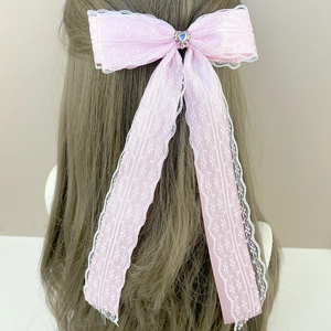 Pink lace bow hair clip featuring a blue heart gemstone and long satin ribbons