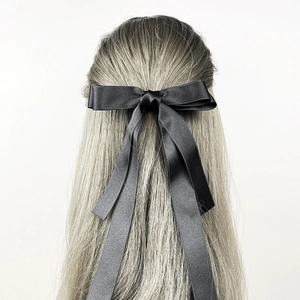 Detail der eleganten schwarzen Satin-Haarklammer mit doppelter Schleife auf blondem Haar