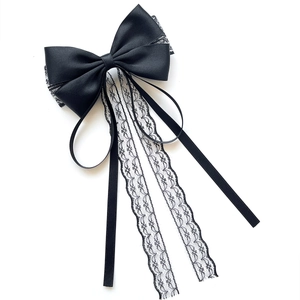 Elegant black satin hair clip with long lace tassels and bow ribbon in a flat lay view