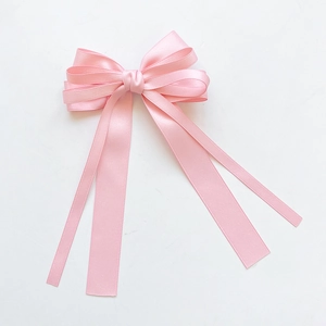 Detail of pink satin layered bow with long flowing ribbons for hair accessory