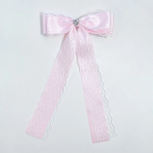 Detail of pink lace ribbon hair clip with heart-shaped rhinestone on white background