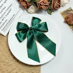 Eleganter dunkelgrüner Satin-Haarclip mit Goldrand auf einer weißen Dekoplatte
