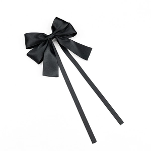 Détail d'un nœud papillon en satin noir élégant avec de longs rubans et texture soyeuse