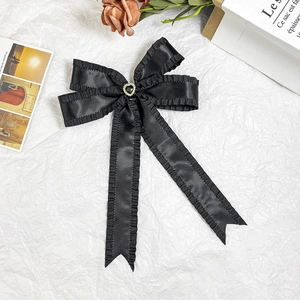 Elegant black ruffle bow hair clip with heart detail on a stylish white background