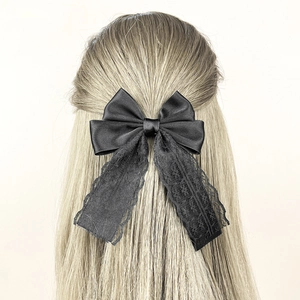 Detail of elegant black lace bow hair clip with satin fabric on golden straight hair