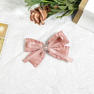 Sweet pink satin bow hair clip with ruffled edges and sparkling rhinestone heart decoration