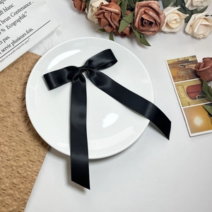 Detail van een elegante zwarte satijnen strik op een wit bord met bloemendecoratie