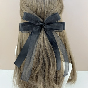 Detail of elegant black multi-layer tulle bow hair clip on brown hair from behind