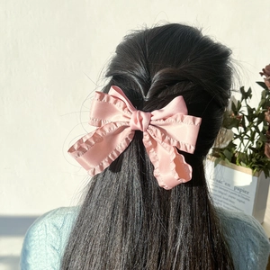 Barrette à nœud rose avec bordure volantée portée sur cheveux mi-attachés et lisses