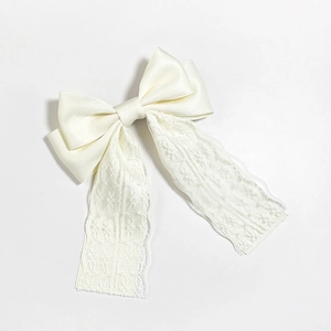 Detailed close-up of cream lace bow hair clip with elegant satin and floral embroidery