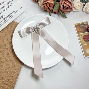 Detail van een elegante champagne satijnen haarstrik met lange linten op bordje