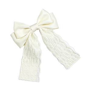 Close-up of cream white satin bow hair clip with intricate floral lace long ribbons
